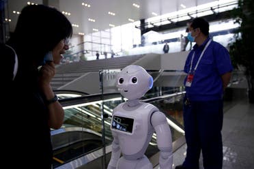 People wearing face masks following the coronavirus disease (COVID-19) outbreak are seen near a robot at the venue for the World Artificial Intelligence Conference (WAIC) in Shanghai, China July 9, 2020. (Reuters)
