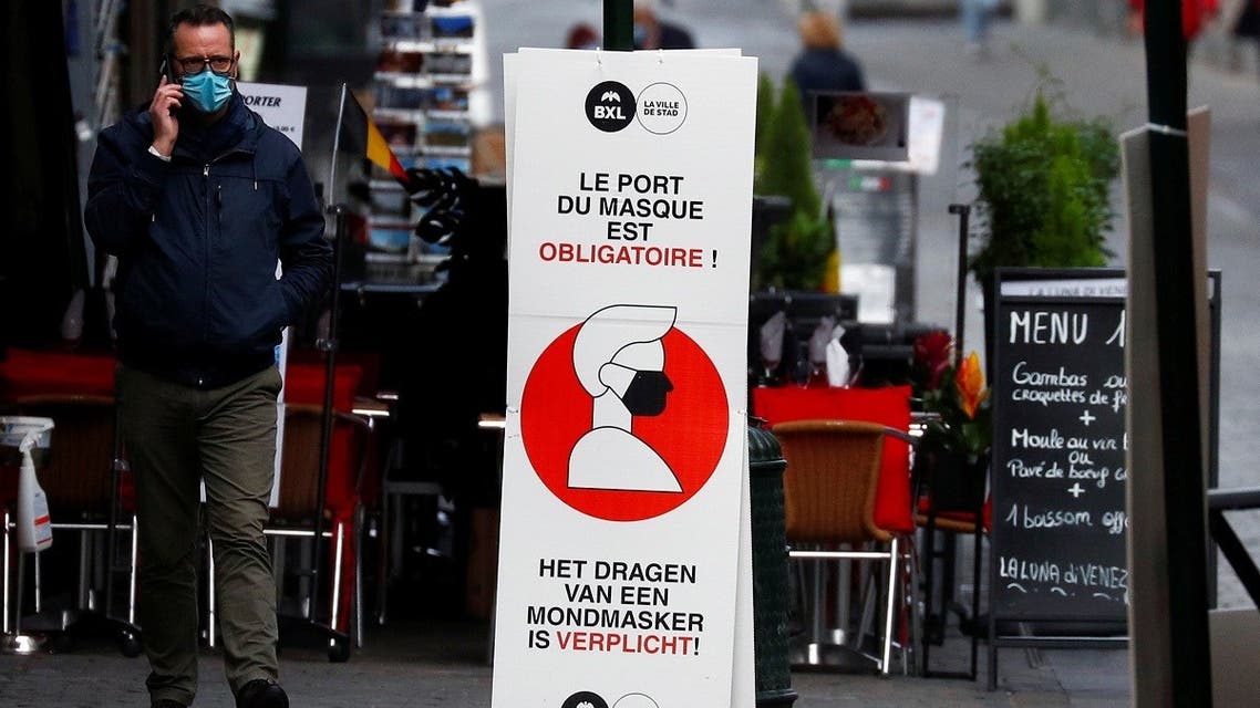 A man walks past a sign announcing the mandatory use of masks in central Brussels, Oct. 16, 2020. (Reuters)