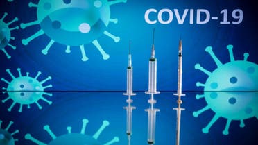 This photograph taken on October 7, 2020 shows syringes on an illustration representing Covid-19 and the novel coronavirus, in Toulouse, southwestern France. (AFP)