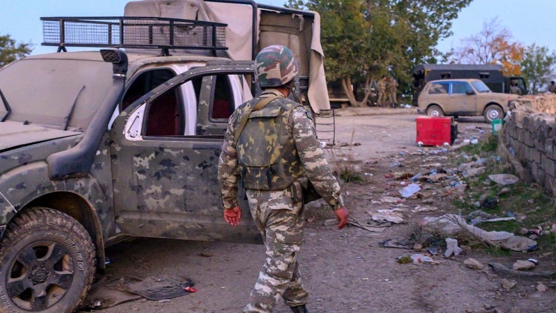 An Azeri soldier walks near a destroyed vehicle in the city of Jabrayil, October 16, 2020. (AFP)