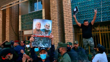 A supporter of an Iran-backed militia holds a poster of Iranian General Qassem Soleimani, deputy commander Abu Mahdi al-Muhandis during a protest by pro-Iranian militiamen and their supporters in Baghdad on Oct. 17, 2020. (AP)