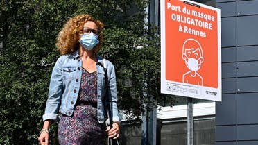 A woman wearing a face mask walks past a sign reading Wearing a mask is mandatory in Rennes in a street of Rennes, western France on September 12, 2020. (AFP)
