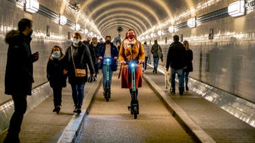 People wear face masks as they ride an E-scooter in the Old Elbe Tunnel in Hamburg, Germany, Thursday, Oct. 15, 2020. To avoid the spread of the coronavirus the use of a face mask in the 117-year-old tunnel under the Elbe river is mandatory. (AP Photo/Michael Probst)