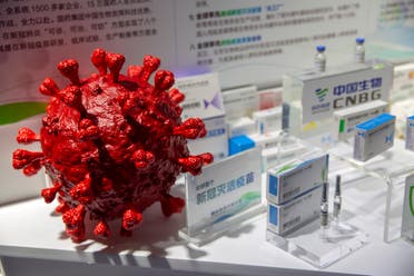A model of a coronavirus is displayed next to boxes for COVID-19 vaccines at an exhibit by Chinese pharmaceutical firm Sinopharm in Beijing, Sept. 5, 2020. (AP/Mark Schiefelbein)