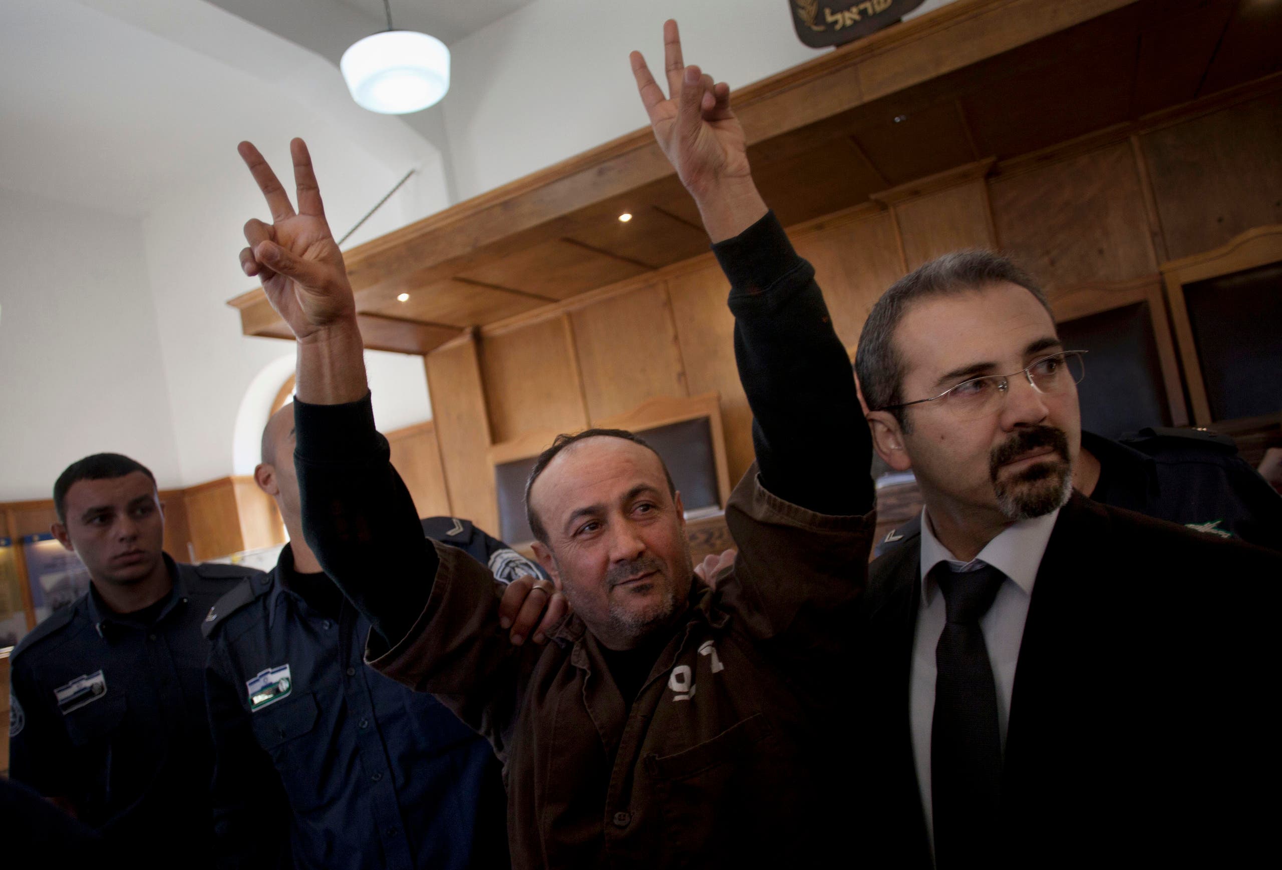 Senior Fatah leader Marwan Barghouti makes the victory sign in front of the media during his arrival to testify in a trial at a Jerusalem court on Jan. 25, 2012. (AP)