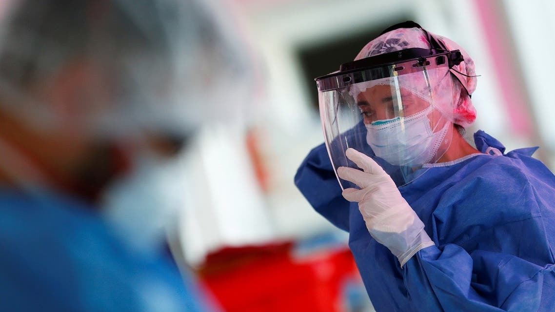 Kinesiologist Maria Luz Porra puts on a mask shield before checking patients suffering from the coronavirus disease (COVID-19) in an intensive care unit of a hospital, on the outskirts of Buenos Aires. (Reuters)