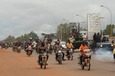Motorcycle taxi operators ride next to military vehicles that escorts the convoy of Russian armored personnel carriers (APC) delivered to the Central African Republic army in Bangui, October 15, 2020. (Camille Laffont/AFP)