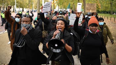 Protestors carry placards and shout slogans against police brutality in Nigeria, as they march along The Mall towards Buckingham Palace in central London on October 24, 2020. (Daniel Leal-Olivas/AFP)