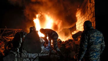 People try to remove car tyres from a car shop on fire after shelling by Azerbaijan's artillery during a military conflict in Stepanakert, the region of Nagorno-Karabakh, on Oct. 23, 2020. (AP)