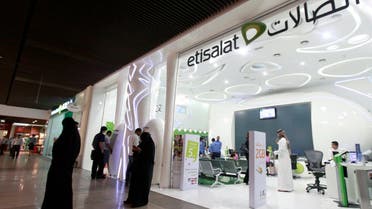 Customers use their mobile phones outside an Etisalat store at a shopping mall in Dubai. (File photo: Reuters)