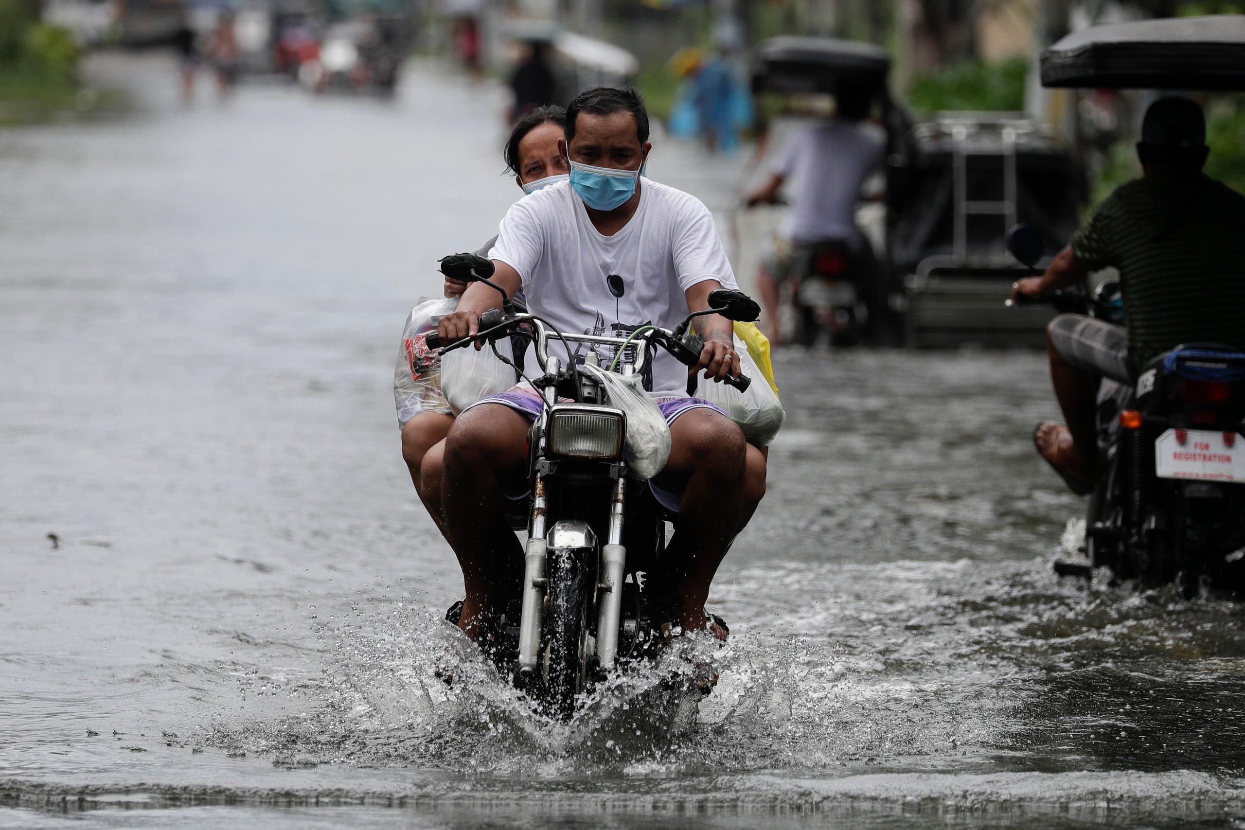 A man driving a bike amid Typhoon Molave in Pampanga province, northern Philippines, Monday, Oct. 26, 2020. (AP)