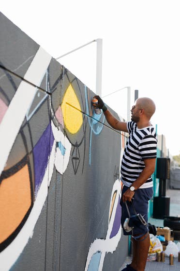 World-renowned artist eL Seed painting a mural  in Alserkal Avenue -- where his studio is based -- that pays tribute to Melehi’s work. (Photo by Angelo Jandri, courtesy Alserkal Avenue)