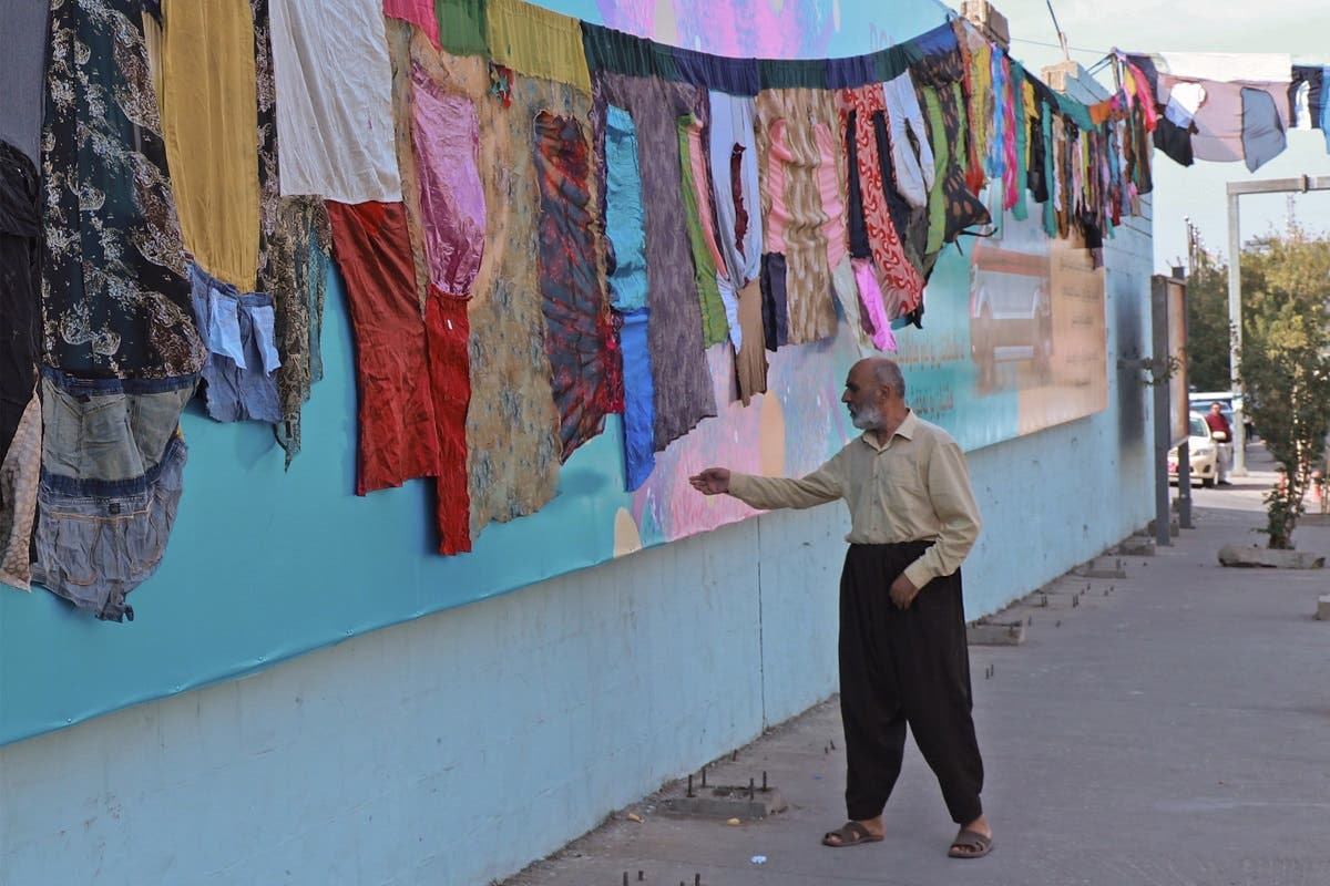 An Iraqi man reaches out to touch an artwork by visual artist Tara Abdallah, in the city of Sulaimaniyah on October 26, 2020. (AFP/Shwan Mohammed)