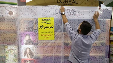 A worker of a mall covers French products in protest against French cartoons of the Prophet Mohammad in Amman, Jordan, October 25, 2020. The cover reads in Arabic In solidarity with the Prophet Mohammad peace be upon him, all French products have been boycotted. (Reuters)