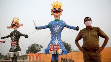 A policeman wearing a protective face mask stands next to the demon King Ravana (L) and his brother Kumbhkarana before they are set on fire during the Hindu festival of Dussehra, amidst the spread of the coronavirus in New Delhi, on October 25, 2020. (Reuters)