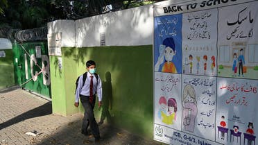 A student wearing a facemask leaves beside a closed school sealed by authorities. (AFP)