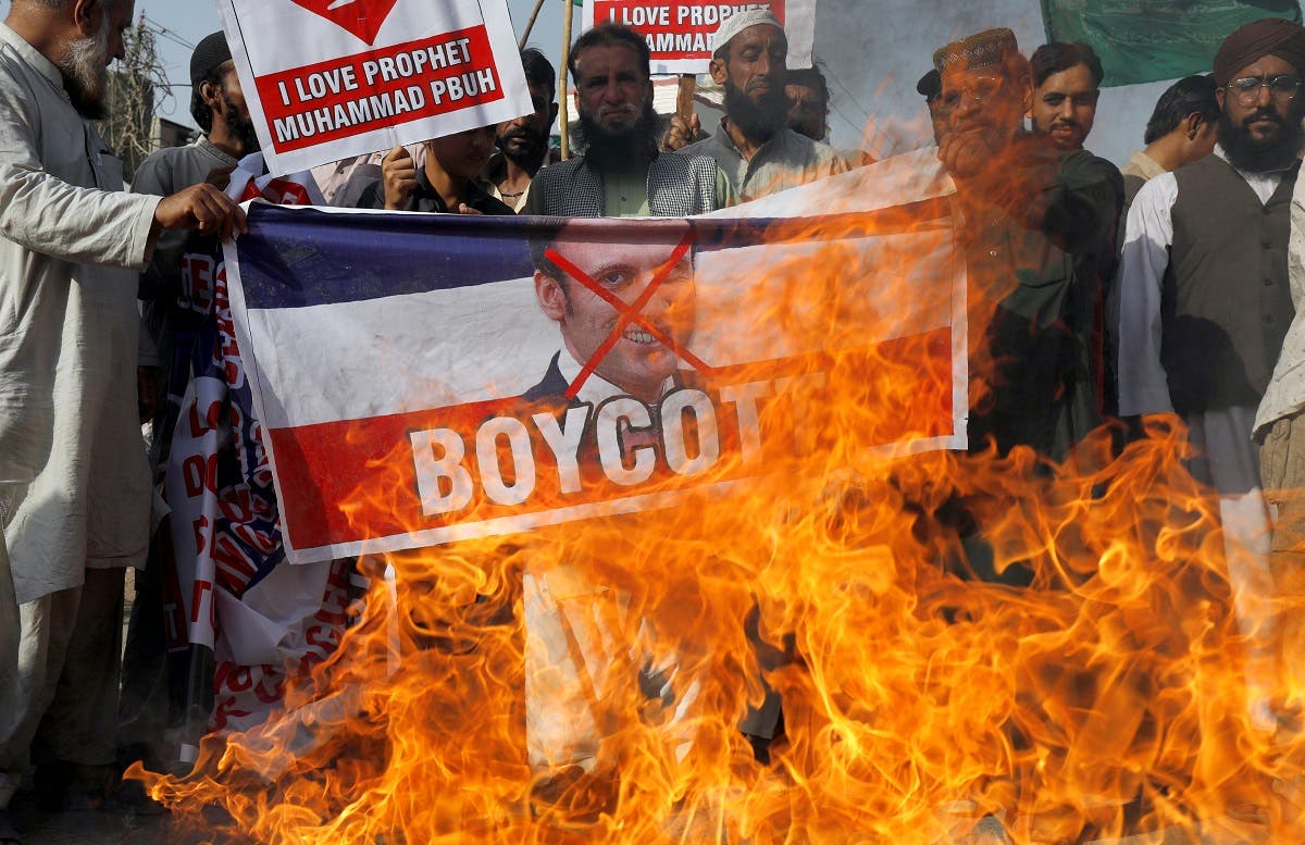 People chant slogans as they set fire to a banner with a crossed-out image of French President Emmanuel Macron during a protest against cartoon publications of Prophet Mohammad in France and Macron's comments, in Karachi, Pakistan. (Reuters)
