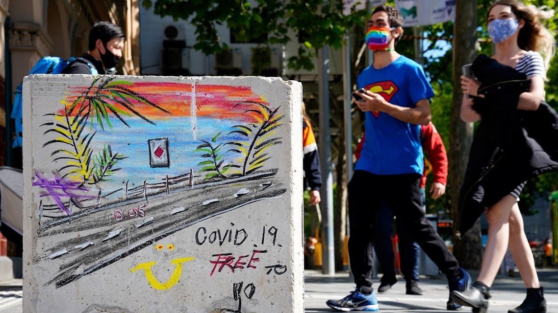 People in face masks walk past a 'COVID-19 Free' sign in Melbourne after coronavirus disease (COVID-19) restrictions were eased for the state of Victoria, Australia, October 28, 2020. (Reuters)