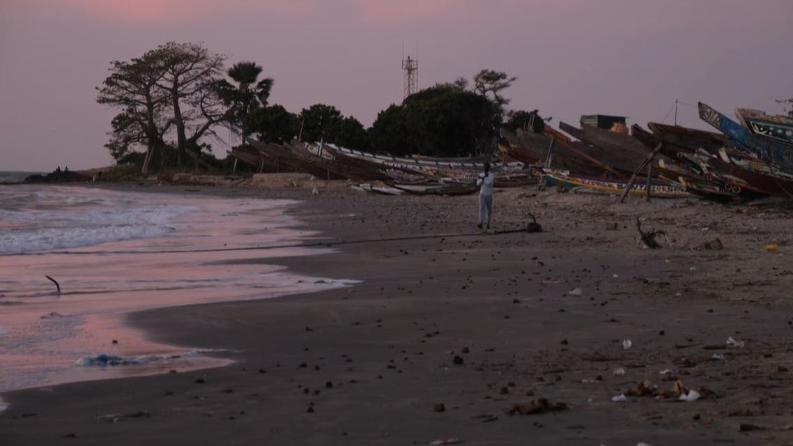 This image grab taken from an AFP video shows boats in the water at a beach, in Barra on December 5, 2019, after at least 62 people died on December 4, 2019 when their makeshift vessel capsized off the coast of Mauritania, including 52 migrants from Gambia.