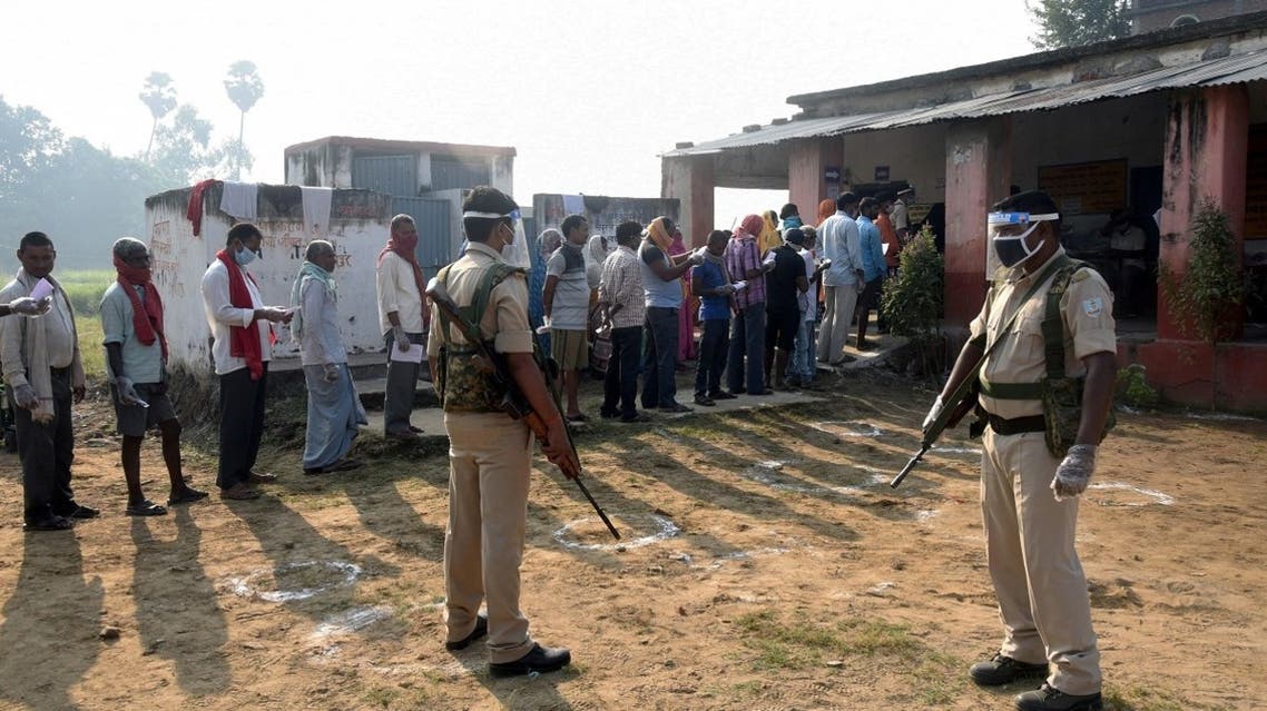 Policemen wearing protective face shields stand guard as voters stand in a queue to cast their vote outside a polling booth during the state assembly election, at a village on the outskirts of Patna, in the eastern state of Bihar, India, on October 28, 2020. (Reuters)