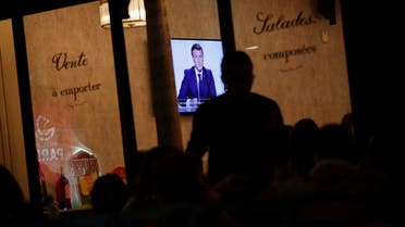People watch French President Emmanuel Macron on a TV screen in a restaurant in Paris as the French leader addresses the nation about the state of the coronavirus disease (COVID-19) outbreak in France, October 28, 2020. REUTERS/Benoit Tessier