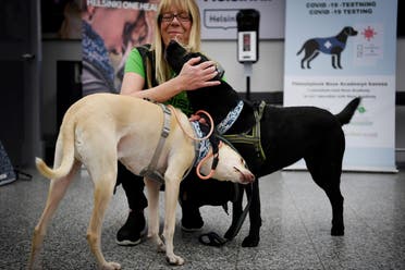 The coronavirus sniffer dogs named Kossi (L) and Miina cuddle with trainer Susanna Paavilainen at the Helsinki airport in Vantaa, Finland, September 22, 2020. (Antti Aimo-Koivisto/Lehtikuva/AFP)