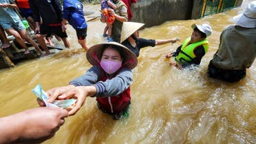 A resident gets money from a volunteer at a flooded area in Quang Binh province, Vietnam October 23, 2020. (Reuters)