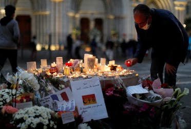 A man lights a candle near the Notre Dame church in tribute to the victims of a deadly knife attack in Nice, France, October 30, 2020. (Reuters/Eric Gaillard)