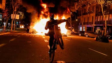 A person rides a bicycle in front of a fire during a protest against the closure of bars and gyms, amidst the coronavirus disease (COVID-19) outbreak, in Barcelona, Spain October 30, 2020. (Reuters)