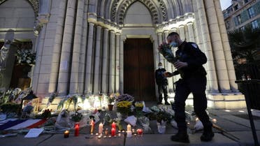 A man lights a candle near the Notre Dame church in tribute to the victims of a deadly knife attack in Nice, France, October 30, 2020. REUTERS/Eric Gaillard