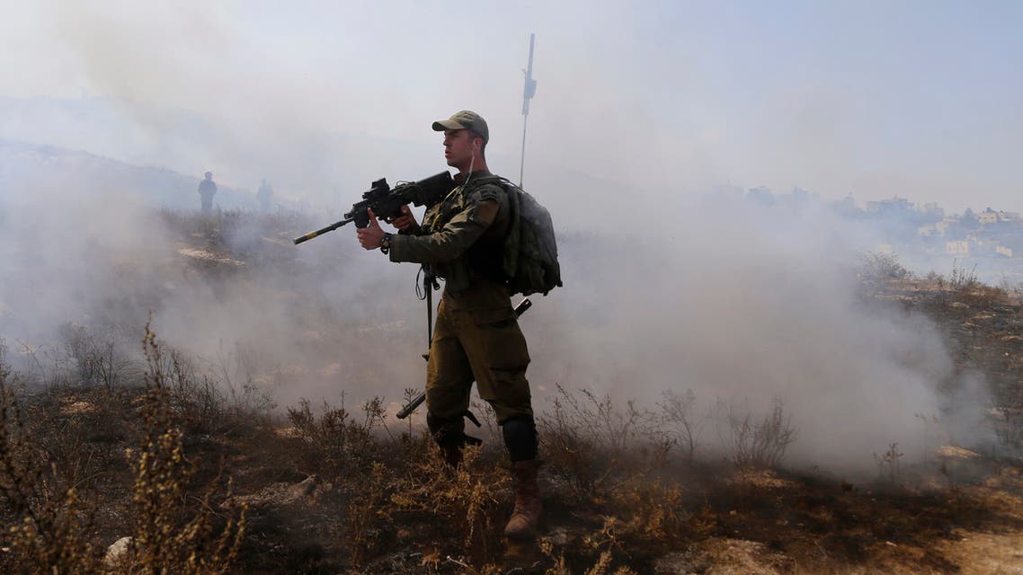An Israeli soldier points his weapon towards a Palestinian demonstrator during clashes in Asira al-Qibliya near the West Bank city of Nablus on Sept. 18, 2020. (AP)