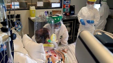 Members of the medical personnel wearing full protective suits treat a patient infected with the coronavirus disease (COVID-19), who is wearing a full covering oxygen mask, in the intensive care unit at the CHU de Charleroi hospital, in Charleroi, Belgium, November 5, 2020. REUTERS/Yves Herman