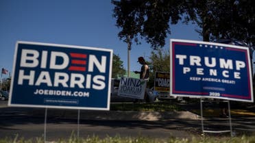 Biden and Trump campaign signs are displayed as voters line-up to cast their ballots during early voting at the Alafaya Branch Library in Orlando, Florida, on October 30, 2020. (AFP)