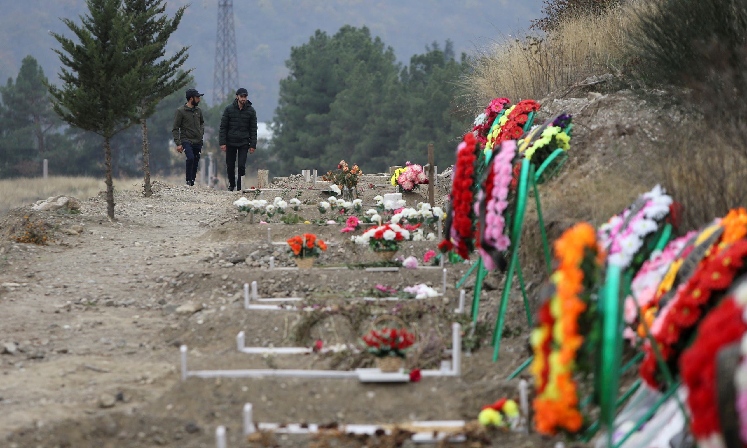 Men walk along graves of soldiers and civilians who were killed during a military conflict over the breakaway region of Nagorno-Karabakh, in Stepanakert. (Reuters)