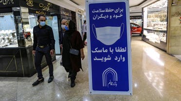 Iranians walk next to a sign advising people to wear masks on their way to shop in Tajrish square in the capital Tehran on November 1, 2020, amid the novel coronavirus pandemic crisis. Iran yesterday announced the expansion beyond Tehran of measures against Covid-19, amid growing calls for a full lockdown after the country posted a string of record highs in deaths and infections.