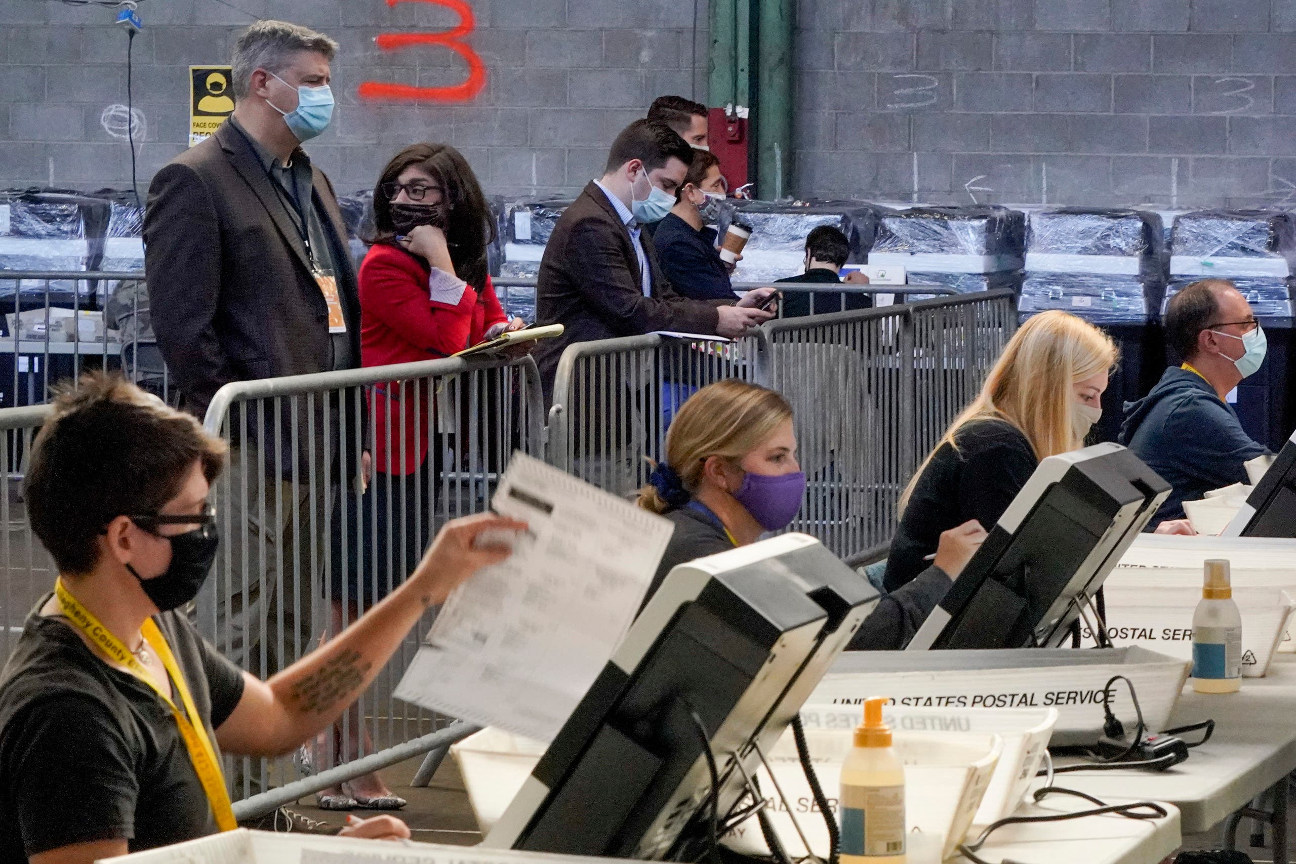 Election observers stand behind a barrier and watch as election office workers process ballots as counting continues from the general election at the Allegheny County elections returns warehouse in Pittsburgh on Nov. 6, 2020. (AP)
