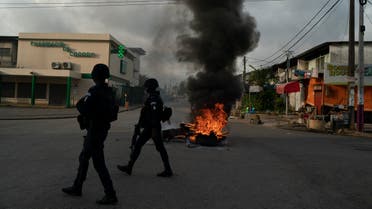 Policemen walk past a burning barricade during a protest after the security forces blocked the access to the house of the former president Henri Konan Bedie, in Abidjan, Ivory Coast, Tuesday, Nov. 3, 2020. (AP)