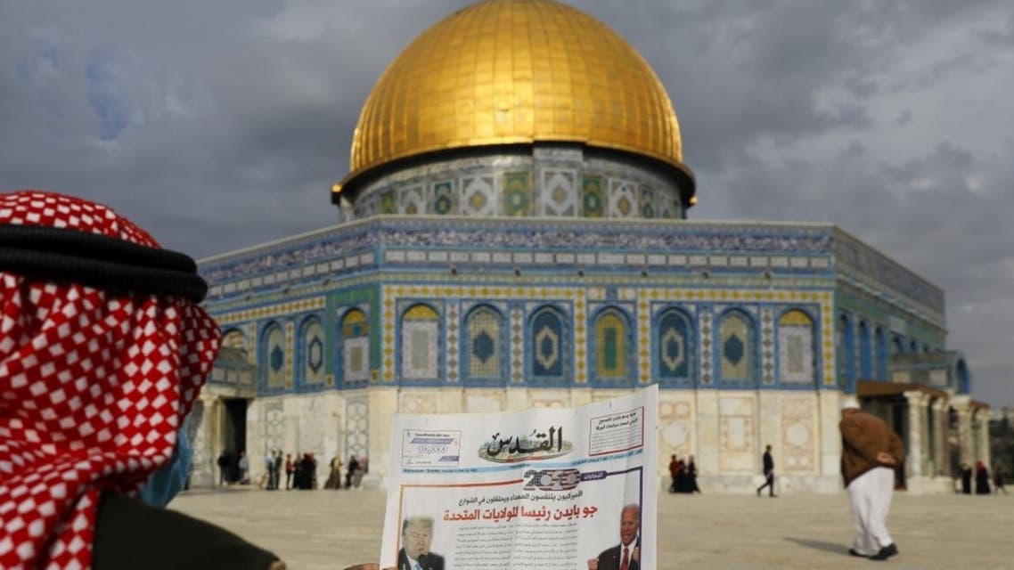 A Palestinian man reads the front page of Al-Quds newspaper, headlined in Arabic Joe Biden the new US President in front of the Dome of the Rock in the al-Aqsa mosque compound, Islam's third holiest site, in the old city of Jerusalem on November 8, 2020. (AFP)