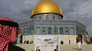 A Palestinian man reads the front page of Al-Quds newspaper, headlined in Arabic Joe Biden the new US President in front of the Dome of the Rock in the al-Aqsa mosque compound, Islam's third holiest site, in the old city of Jerusalem on November 8, 2020. (AFP)