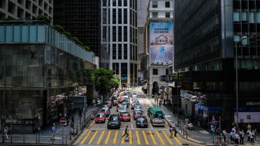 A pedestrian (C) runs across a pedestrian crossing between commercial buildings in the Central district of Hong Kong on July 16, 2020. Beijing's tough new security law and President Donald Trump's order to rescind special trading privileges have blunted Hong Kong's competitive edge and risk turning the finance hub into just another Chinese city, analysts warn.