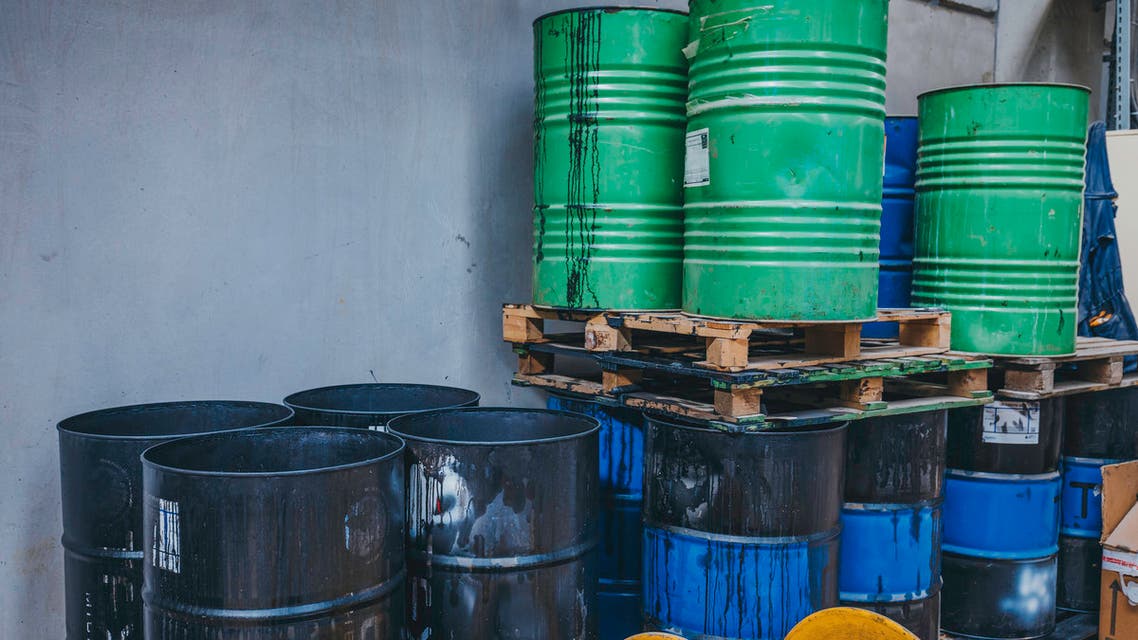 Old iron barrels in warehouse stock photo Old chemical barrels. Blue and orange oil drum. Steel oil tank. Toxic waste warehouse. Hazard chemical barrel with warning label. Industrial waste in metal drum. Hazard waste storage in factory.
