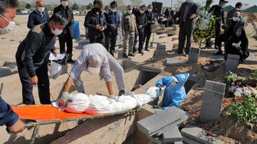The body of a person who died from COVID-19 is interred as mourner look on, at the Behesht-e-Zahra cemetery on the outskirts of Tehran, Iran, Sunday, Nov. 1, 2020. The cemetery is struggling to keep up with the coronavirus pandemic ravaging Iran, with double the usual number of bodies arriving each day and grave diggers excavating thousands of new plots. (AP Photo/Ebrahim Noroozi)