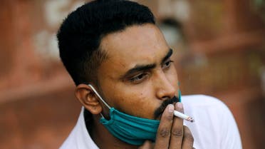 A man wearing a protective face mask smokes a cigarette amidst the spread of the coronavirus disease (COVID-19) in the old quarters of Delhi, India, October 20, 2020. (Reuters)