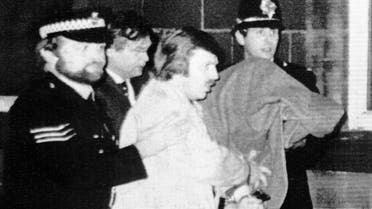 This January 5, 1981, file photo shows Peter William Sutcliffe, 35, under a blanket at right, being led from Dewsbury Magistrates Court in Dewsbury by police officers. (AP)