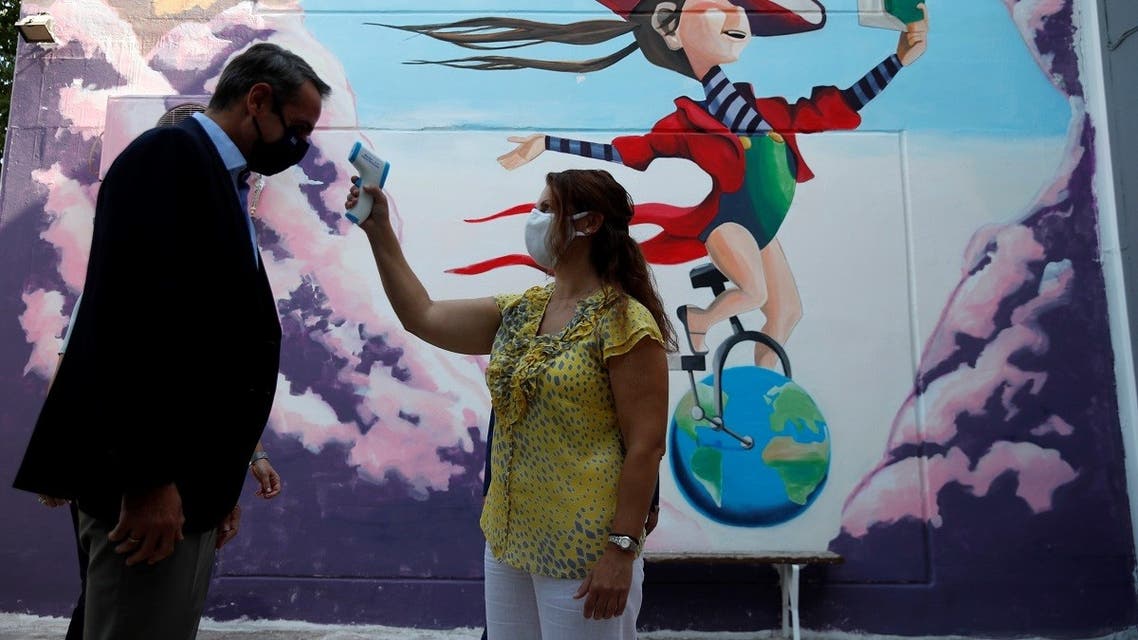 A teacher takes the temperature of Greece’s PM Kyriakos Mitsotakis as he arrives at a primary school on the first day of class of the new academic year in Athens, on September 14, 2020. (Thanassis Stavrakis/Pool/AFP)