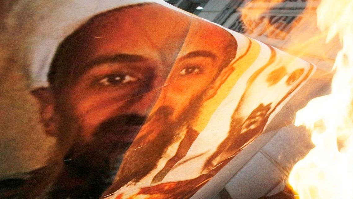 A man burns a portrait of al-Qaeda leader Osama bin Laden, left, and Jordanian-born terrorist mastermind Abu Musab Al-Zarqawi, Jan. 3, 2010. (AP)