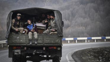 Armenian soldiers sit in the back of a truck as they drive along a road outside Kalbadjar on November 15, 2020. (AFP)