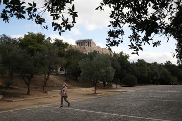 A woman makes her way, as the Parthenon Temple is seen atop the ancient Acropolis in Athens. (Reuters)