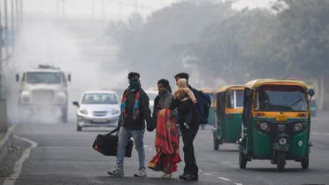 People cross a street as motorists drive past amid smoggy conditions in New Delhi on November 15, 2020. 