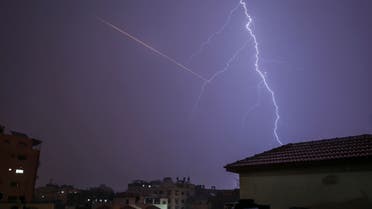 This picture taken from Gaza City shows lightning flashing over buildings as the flair of a rocket launched is seen nearby during a thunderstorm in Gaza city. (AFP)